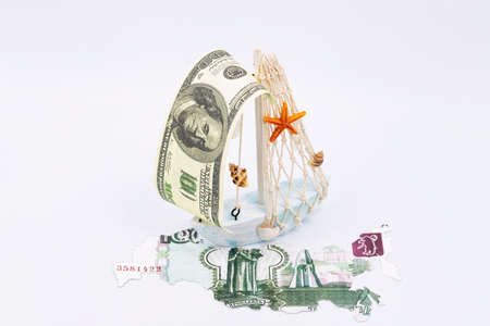A toy ship with a sail made of a hundred-dollar bill sailed to the shores of Russiaの写真素材