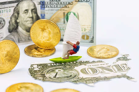 Toy windsurfer, gold bitcoins and US card from dollarsの写真素材