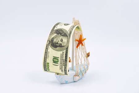 A decorative toy ship with a sail of one hundred dollar bills sailsの写真素材