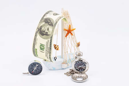 crumbling carablica with a sail made of hundred-dollar bill, compass and pocket watchの写真素材