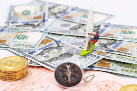 Toy windsurfer rides on waves of money and passport pagesの写真素材