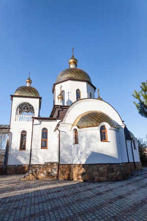 Orthodox church with white camps, bell tower and gilded domes in clear weatherの写真素材