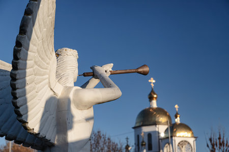 Sculpture of angel with a wind instrument against the background of the golden domes of the Orthodox Churchの写真素材