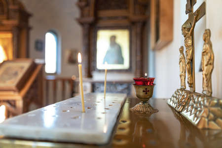 Candles burn in front of the iconostasis and the cross with a crucifix in a small Orthodox chapelの写真素材