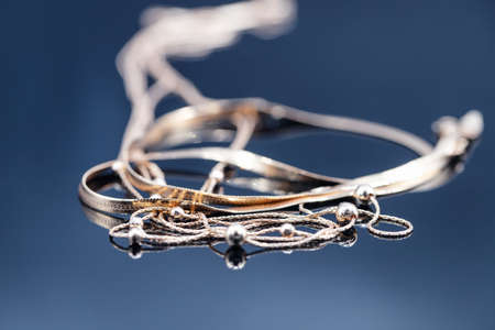 Gold rings with different precious stones lie surrounded by beautiful gold chainsの写真素材