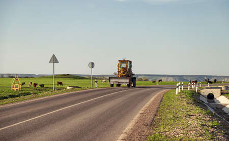 Special equipment stands on side of the road in countryside. Nearby, livestock will fall on a green meadowの写真素材