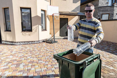 A middle-aged man throws plastic bottles in a garbage canの写真素材