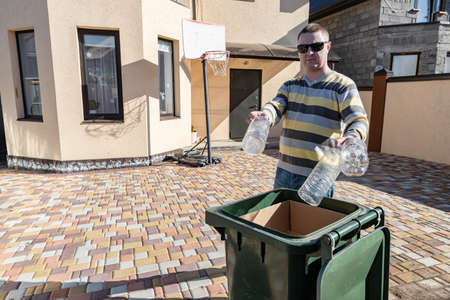 A middle-aged man throws plastic bottles in a garbage canの写真素材