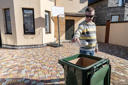A middle-aged man throws plastic bottles in a garbage canの写真素材