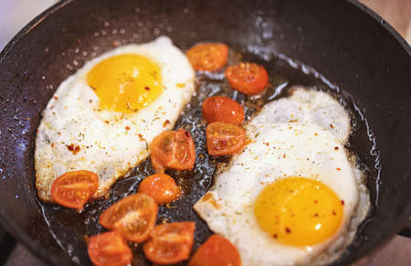 scrambled eggs with spices and small red tomatoesの写真素材