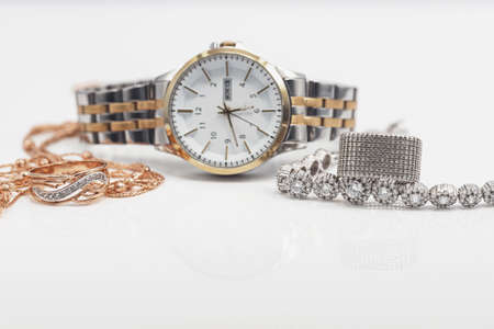 Gold and silver jewelry lies next to original womens watchの写真素材
