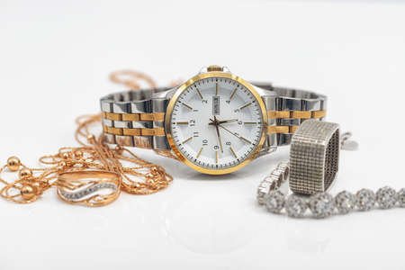 Gold and silver jewelry lies next to original womens watchの写真素材