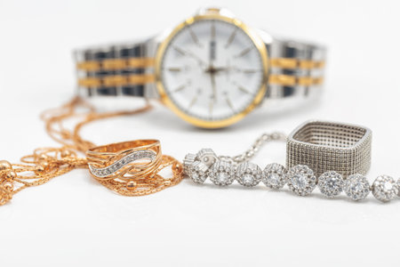 Gold and silver jewelry lies next to original womens watchの写真素材