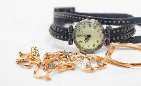 Womens wristwatch with leather strap lies next to the gold chain and necklace with precious stonesの写真素材