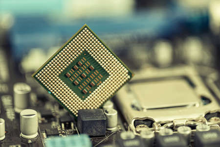 An old computer processor stands on background of motherboardの写真素材