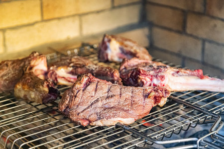 Beef steaks on the bone are grilled on a grate over the coalsの写真素材
