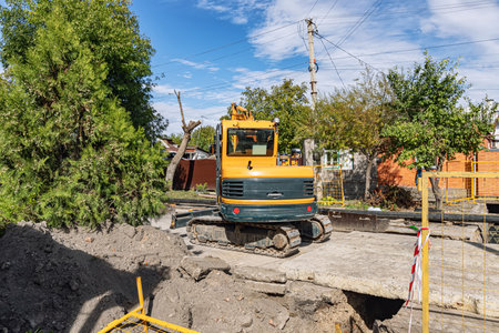 Carrying out work on laying a new gas pipeline from polymeric materials in a cottage settlement using an excavatorの写真素材