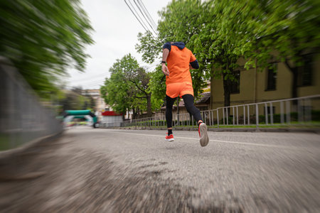 An athlete in an orange sports uniform accelerates before the finish lineの写真素材
