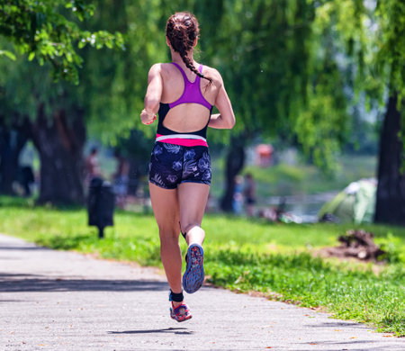 Girl athlete running along the track in the park at the stage of the triathlon distanceの写真素材