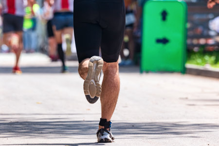 The legs of an athlete dressed in sports ammunition, running on asphalt, a marathon distanceの写真素材