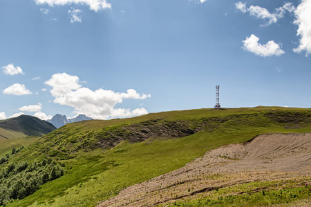 Mountain landscape with green slopes, cliffs, glaciers and white fluffy clouds in the skyの写真素材