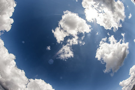 The rays of the sun break through white fluffy clouds. Sky landscape in the mountains