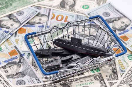 Plastic models of the Project 636 Varshavyanka submarine are lying in a supermarket cart as a purchase against the background of moneyの写真素材