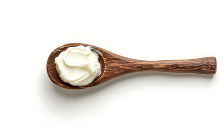 Sour cream in wooden spoon on white backgroundの素材