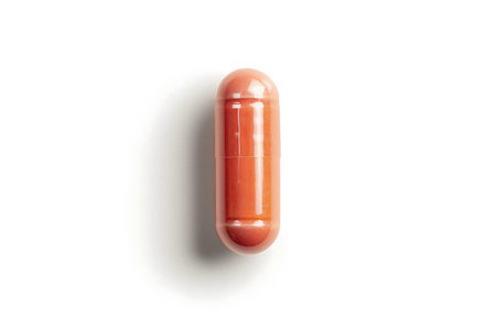 A white pill with orange specks isolated on white backgroundの素材