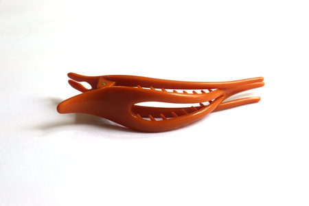 Closeup of an orange hair claw clip on a white background with soft shadowsの写真素材