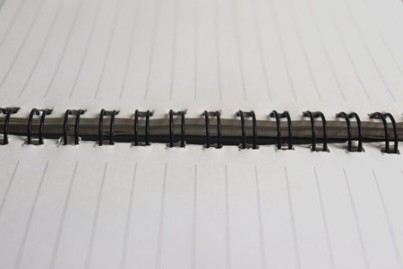 Closeup of an open notebook with black spiral binding and lined white paperの写真素材