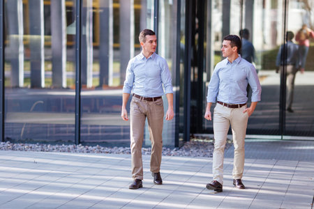 Two businessman walking and talking about business with street city blur backgroundの写真素材