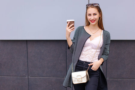 One girl stand near the wall with cup of coffeeの写真素材