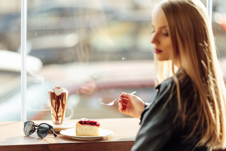 Pretty girl hold a plate of delicious cake and waer glasses. Sun shine photo with girl eat her cakeの写真素材