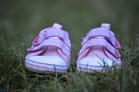 Cute baby pink shoes with green backgroundの写真素材