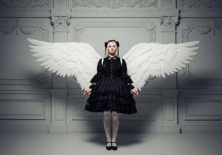 Cute little girl in black dress with angel wings over gray backgroundの素材