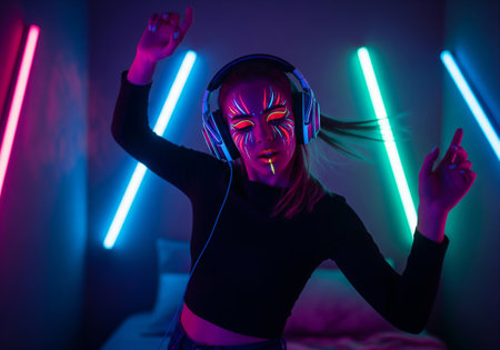 Portrait of a young girl in headphones listening to music and dancing at homeの素材