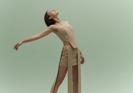 beautiful young woman in beige skirt and blouse posing on greyの素材