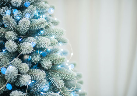 Christmas tree with blue lights and bokeh on white curtain backgroundの素材