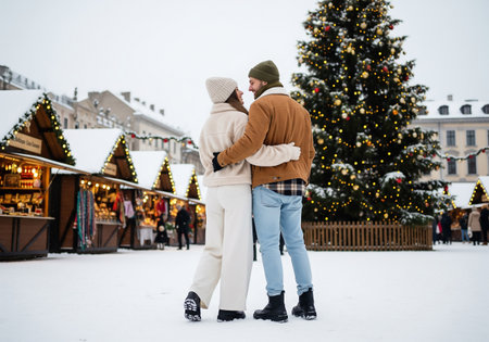 Young loving couple in warm sweaters on the background of the Christmas marketの素材