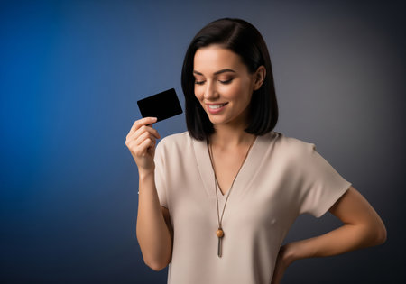 Beautiful young woman holding a blank credit card on a blue backgroundの素材