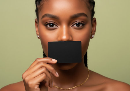 Beautiful african american woman holding blank card on green backgroundの素材