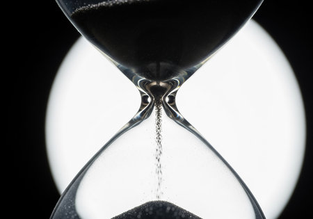 Hourglass close-up on black background. Concept of time passing.の素材