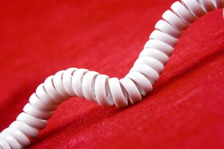 A white telephone cord with red background.の写真素材