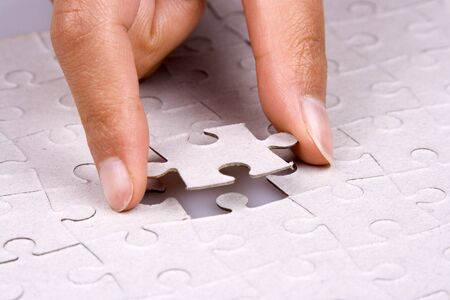 Close up of hand playing jigsaw puzzle.