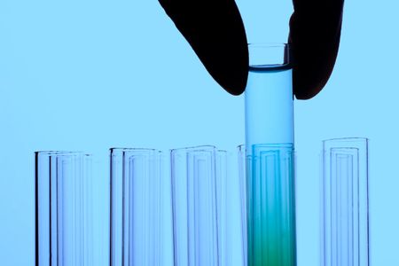 A hand holding a test tube in plain background.