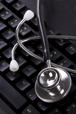 Black color computer keyboard with stethoscope on top.