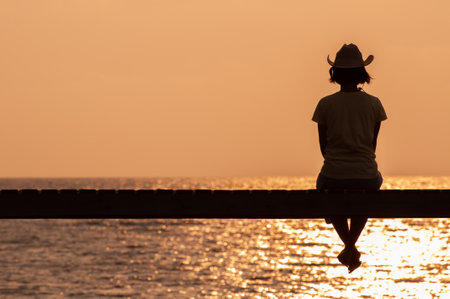 Young woman sitting on edge looks out at view stock photoの写真素材
