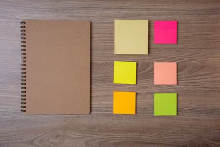 Notebook with brown cover and ring at the edge put on brown wooden table with post-it