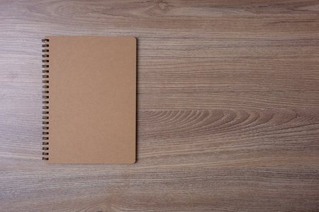 Notebook with brown cover and ring at the edge put on brown wooden tableの写真素材